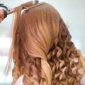 pexels-photo-3065209-3065209 Close-up of a stylist curling blonde hair into glamorous curls at a salon.